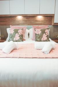 Harbour View Hayling Island في Hayling Island: سرير كبير عليه وسائد وردية وأخضر