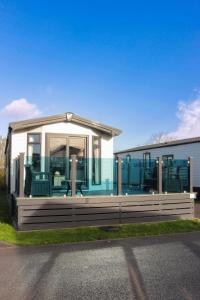 Harbour View Hayling Island في Hayling Island: منزل متنقل مع نافذة كبيرة وكراسي