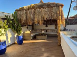 een patio met een bank onder een rieten parasol bij RIAD NOLITA & SPA Kasbah in Marrakesh