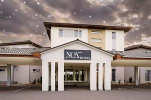 Un gran edificio blanco con un cartel en él. en Noa Panzio, en Vecsés