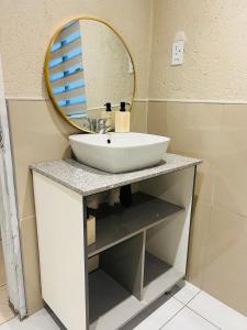 Emgwenyeni Guest house في منزيني: حمام مزود بحوض ومِرآة