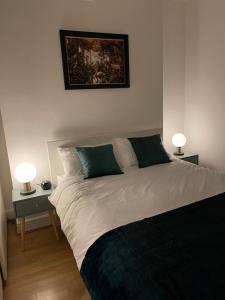 a bed in a bedroom with two lamps on tables at Acon Heights in London