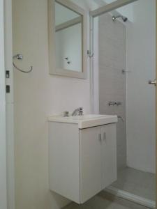 y baño blanco con lavabo y ducha. en Apartamentos Don Bosco en Paso de los Libres