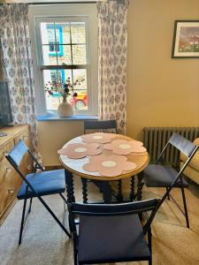 a table and chairs in a room with a window at Maggies Cottage in Little Broughton +13 photos
