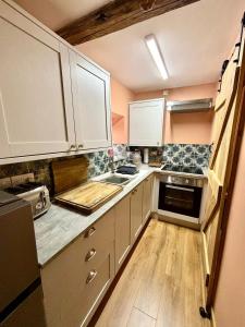 a kitchen with white cabinets and a wooden floor at Maggies Cottage in Little Broughton