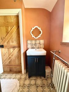 a bathroom with a sink and a wooden door at Maggies Cottage in Little Broughton