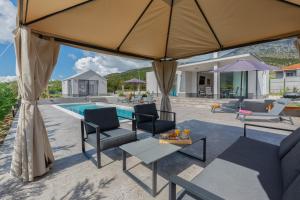 a patio with chairs and a pool with a large umbrella at Holiday House Omis - Naklice in Omiš
