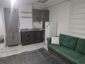 a living room with a green couch and a kitchen at Umut apart otel in Urfa