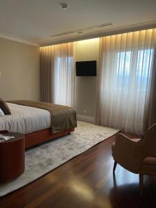 Schlafzimmer mit einem Bett, einem TV und Vorhängen in der Unterkunft Casa Correio Boutique Hotel in Valença