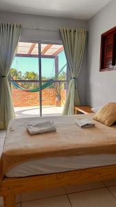 een groot bed in een slaapkamer met een groot raam bij Flats Villa Gelú in Barra Grande