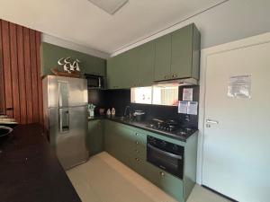 cocina con armarios verdes y nevera de acero inoxidable en Dúplex con impresionantes vistas al mar RAT002, en Perequê