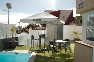 een tafel en stoelen onder een parasol naast een zwembad bij Luxe Loma 2 in Mogán