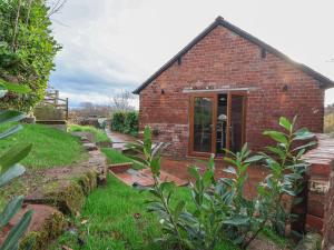 een klein bakstenen gebouw met een deur in een tuin bij Quarry Barn in Gresford