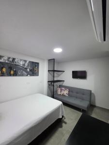 ELEGANTE, CÓMODO Y MODERNO APARTAMENTO - SUR DE CALI في كالي: غرفة نوم بسرير ابيض واريكة