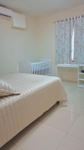 a white bedroom with a bed and a window at Casa familiar completa con patio grande y estacionamiento en zona tranquila in Ciudad del Este
