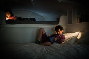 a young boy sitting on a bed reading a book at Burren Glamping in Kilfenora