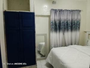 Top Crew Cottage Kempton Park في كيمبتون بارك: غرفة نوم بها سرير ومرآة ونافذة