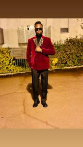 een man in een rode jas staat op een stoep. bij Fuanani in Montgeron