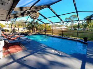 a swimming pool with a glassconservatory with two chairs at st pete pool house in St Petersburg