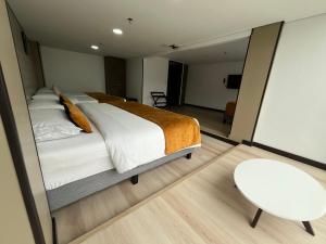 a bedroom with a large bed and a white chair at Hotel WLH Gold Bogota in Bogotá