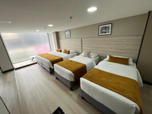 a hotel room with three beds and a window at Hotel WLH Gold Bogota in Bogotá
