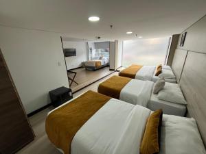 a hotel room with two beds and a couch at Hotel WLH Gold Bogota in Bogotá