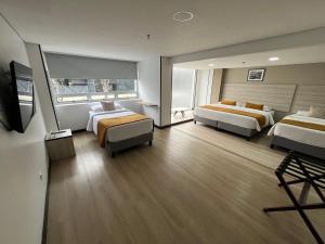 a hotel room with two beds and a flat screen tv at Hotel WLH Gold Bogota in Bogotá