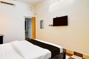 Hotel O Rasulgarh Square Bus Stop Formerly Hotel Rose Inn في Bālianta: غرفة نوم بها سرير وتلفزيون على الحائط