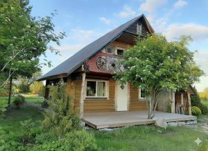 a small wooden house with a porch and a tree at Kadakasuitsu Loodustalu in Saareküla
