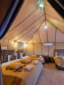 een kamer met drie bedden in een tent bij Glamping Dunes Merzouga in Merzouga