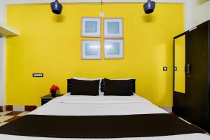 Hotel O Rasulgarh Square Bus Stop Formerly Hotel Rose Inn في Bālianta: غرفة نوم بسرير كبير وبجدار اصفر