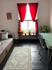 a living room with a window with red curtains at Pensione Popolo in Montreal