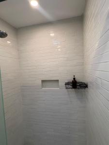 NIDO Hotel في سان ميغيل دي الليندي: حمام ذو بلاط أبيض يجلس فيه رجل على رف