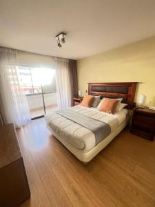 Un dormitorio con una cama grande y una ventana grande. en Departamento Coyancura, en Santiago