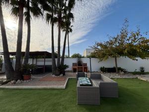 a backyard with palm trees and a couch and a table at CHALET directo al MAR in Benicarló +34 photos
