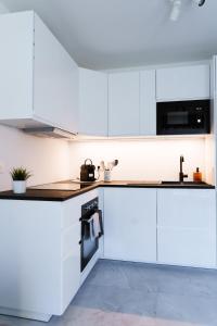 uma cozinha com armários brancos e uma bancada em L'Alexandra em Noisy-le-Grand