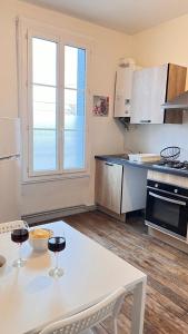 L'oasis de l'Yonne في Migennes: مطبخ مع طاولة وكأسين من النبيذ