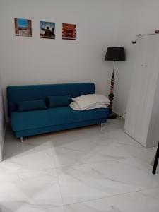 Il Don Giovanni Room في بارليتا: أريكة زرقاء في غرفة بيضاء مع مصباح