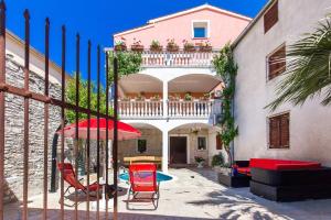 ein Haus mit einem Balkon mit Stühlen und einem Sonnenschirm in der Unterkunft Apartments Samia in Medulin
