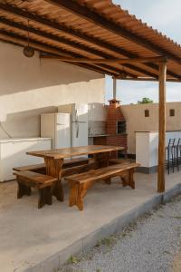 a picnic table and two benches under a pavilion at Residencial céu aberto in Porto Seguro