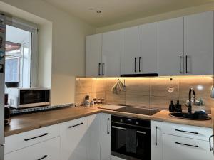 a kitchen with white cabinets and a sink and a microwave at Gusterita Hideaway in Sibiu +16 photos