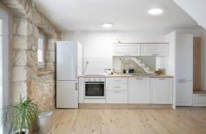 een keuken met witte kasten en een witte koelkast bij House Bernarda in Medulin