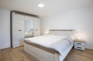 een witte slaapkamer met een groot bed en een kast bij House Bernarda in Medulin +24 foto's