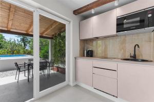 una cucina con armadi bianchi e un patio con tavolo di Villa Alis a Karpinjan