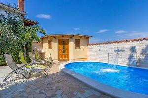 a swimming pool with two chairs and a house at Villa Cera in Vodnjan