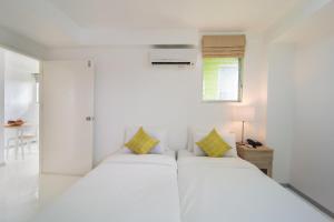 um quarto branco com 2 camas e uma janela em ST88 Residence em Nonthaburi