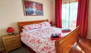 The Beach House! Just Steps from the Beach & Attractions - Perfect for Couples & Family Stays with Private Parking, Large Garden & Fast Free WiFi - The Perfect Seaside Getaway to Sutton on Sea في ساتون أون سي: غرفة نوم بسرير كبير مع ستائر حمراء