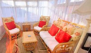 The Beach House! Just Steps from the Beach & Attractions - Perfect for Couples & Family Stays with Private Parking, Large Garden & Fast Free WiFi - The Perfect Seaside Getaway to Sutton on Sea في ساتون أون سي: غرفة معيشة مع كرسيين وأريكة مع وسائد حمراء