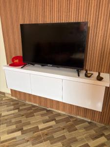 een flatscreen-tv op de top van een wit entertainment center bij Breeze surf lodge in Tamraght Ouzdar
