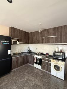 ルハン・デ・クージョにあるLos Álamos - Casa moderna y ampliaのキッチン(木製キャビネット、洗濯機、乾燥機付)